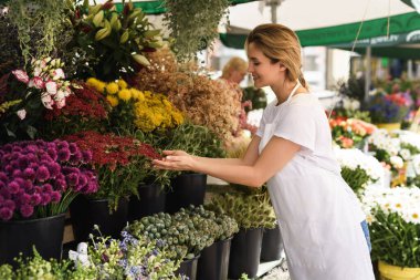 Çiçekçi dükkanında çalışan genç ve güzel bir kadın.