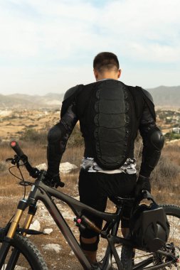 Profesyonel yokuş aşağı sürücüsü koruyucu ekipman ve bisikletiyle donatılmış.