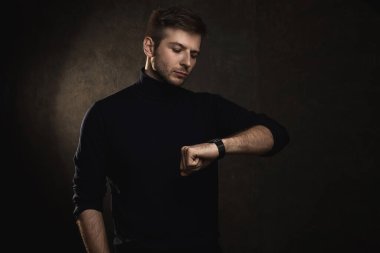 Polo yaka giyen yakışıklı bir adamın portresi zamanı kontrol ediyor.