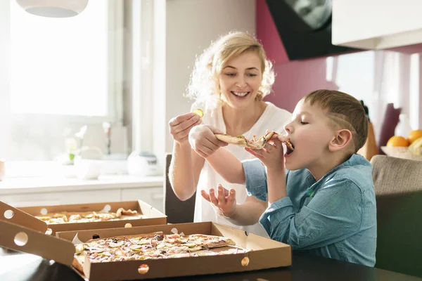 妈妈和她可爱的儿子在家里吃美味的意大利披萨 — 图库照片