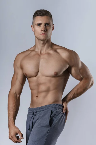 Junger Bodybuilder Zeigt Seinen Muskulösen Körper Vor Grauem Hintergrund — Stockfoto