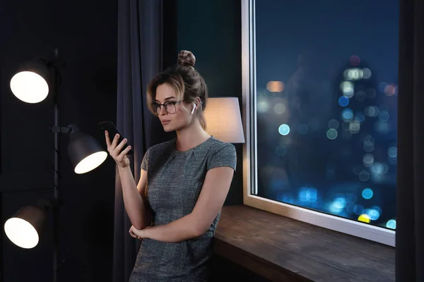 Young Business Woman Using Wireless Earbuds Smartphone Late Night Work — Stock Photo, Image