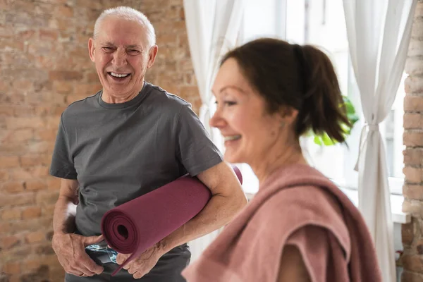 Two cheerful and active old people with exercising mats. Happy elderly couple ready for workout.