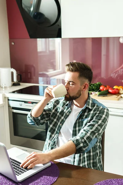 Jovem Homem Bonito Bebendo Café Chá Usando Laptop Cozinha — Fotografia de Stock