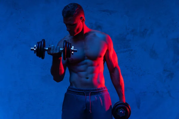 Homem Fisiculturista Jovem Muscular Exercitando Com Halteres Luz Néon Colorido — Fotografia de Stock