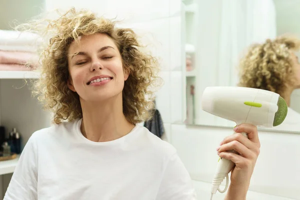 Mladá Šťastná Žena Použití Fén Pro Její Kudrnaté Vlasy Koupelně — Stock fotografie