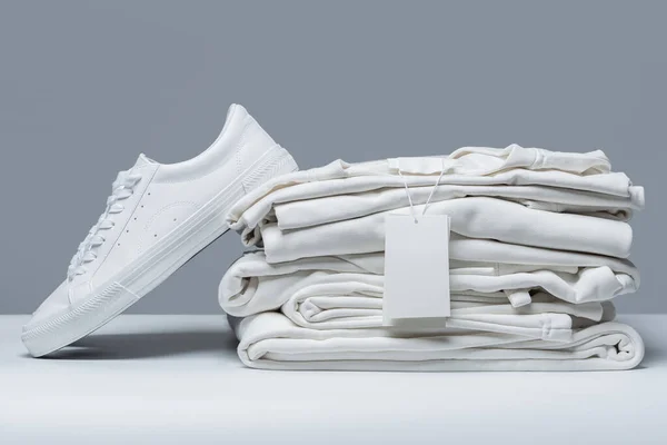 Pilha Roupas Brancas Novas Com Uma Etiqueta Vestuário Branco Fundo — Fotografia de Stock