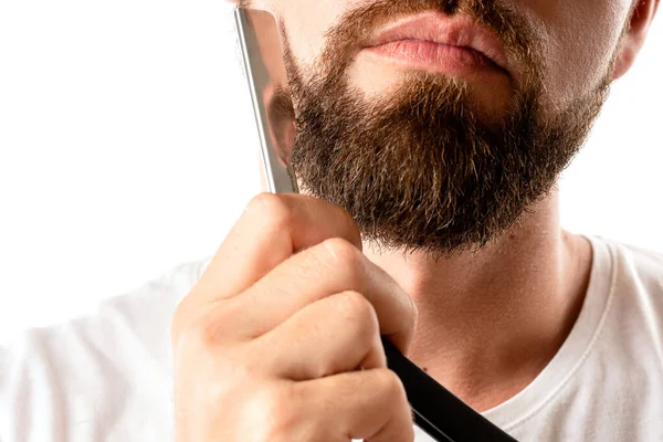 男は白い背景に真っ直ぐな剃刀で太い髭を剃っている — ストック写真