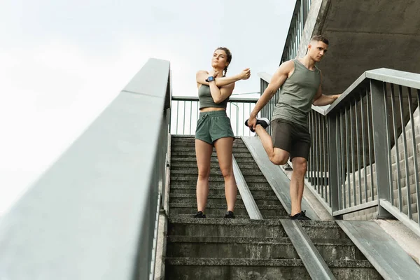 Confident athletic couple are warming up before street workout