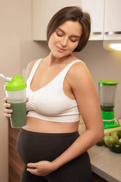 Молодая Беременная Женщина Держит Шейкер Зеленым Протеиновым Коктейлем Дома — стоковое фото