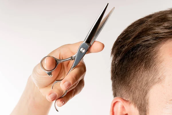 Closeup of hairdresser\'s hand with a scissors and man\'s hair