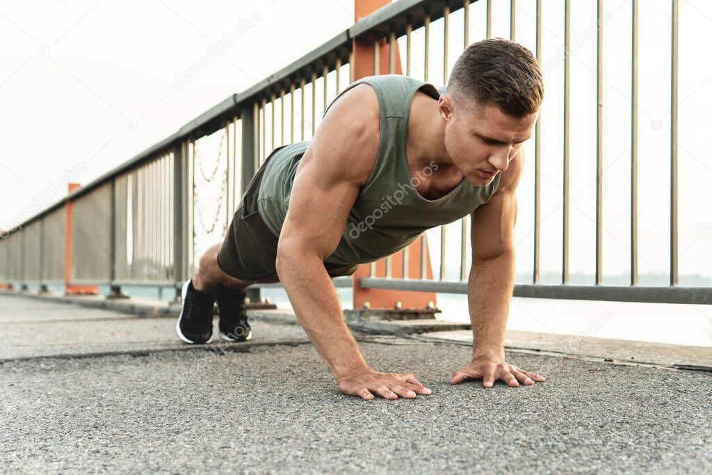 Young and muscular man is doing push-ups during calisthenic workout on a street