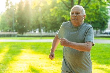 Şehir parkında koşu yaparken aktif yaşlı bir adam.