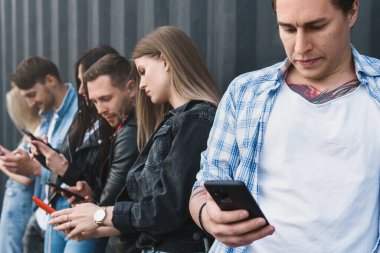 Bir grup genç ve şık arkadaş gerçek iletişim yerine akıllı telefonları kullanıyor.