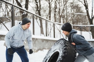 Çapraz antrenman dışarıda. Antrenör ve bayan müşterisi soğuk kış ve karlı günde lastikle antrenman yapıyorlar..