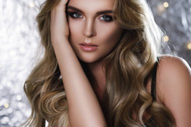 Stüdyoda güzel kıvırcık saçlı ve profesyonel makyajlı muhteşem bir kadının portresi.