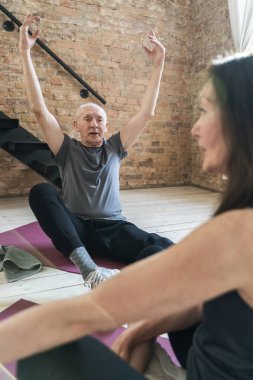 Spor yaparken veya evde yoga yaparken iki aktif yaşlı insan