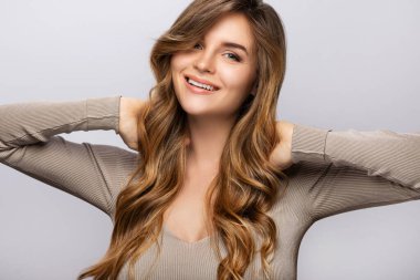 Gri arka planda kıvırcık saçlı güzel bir kadının portresi.