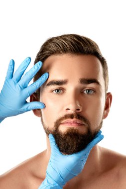 Beyaz arka planda estetik ameliyat öncesi kontrol sırasında yakışıklı bir adam.