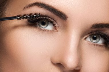 Maksimum miktarda yapay kirpik için kadın yüzüne ve rimel asasına yakın çekim