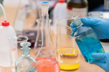 Farklı kimyasal şişeler ve bilim adamı elleri.
