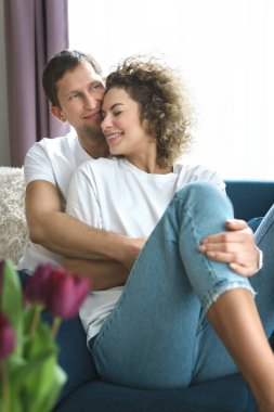 Genç ve mutlu bir çift kanepede oturuyor ve evde dinleniyor.