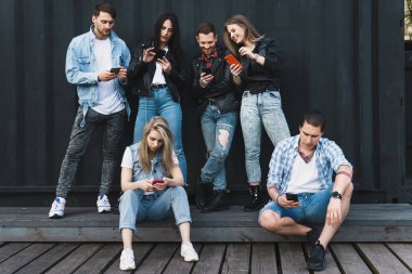 Bir grup genç ve şık arkadaş gerçek iletişim yerine akıllı telefonları kullanıyor.