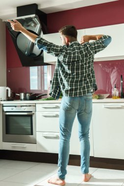 Genç yakışıklı adam güneşli sabahlarda yemek pişirirken mutfakta dans ediyor.