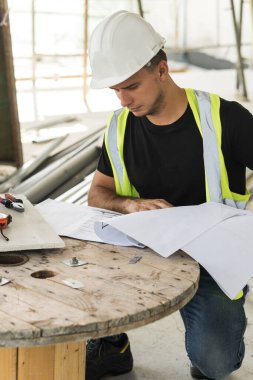 Young, inşaat sahasının planları üzerinde çalışıyor.