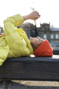 Sarı puf ve turuncu örgü şapka giyen şık bir kızın portresi. 