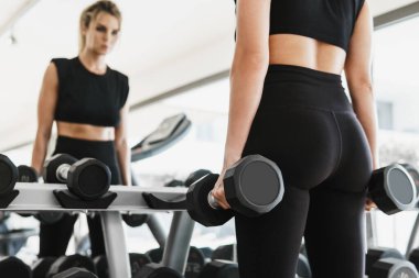 Spor salonundaki halterlerle spor yaparken genç bir atletik kadın.