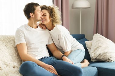 Genç ve mutlu bir çift kanepede oturuyor ve evde dinleniyor.