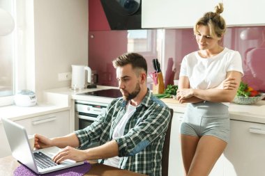 Genç ve mutlu çift sabah mutfakta dizüstü bilgisayar kullanıyor.