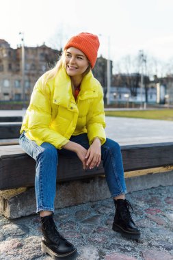 Sarı puf ve turuncu örgü şapka giyen şık bir kızın portresi. 