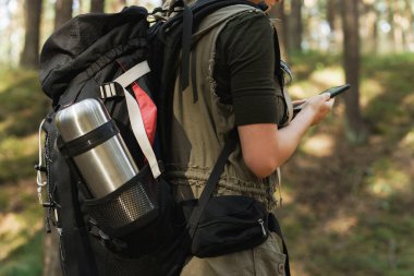 Yeşil ormanda büyük sırt çantalı genç bir bayan yürüyüşçü.