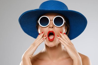 Mavi şapkalı ve güneş gözlüklü genç ve güzel bayan tatile hazır.