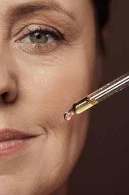 Yenilenme serumlu kadın yüzü ve damlatıcıya yakın çekim