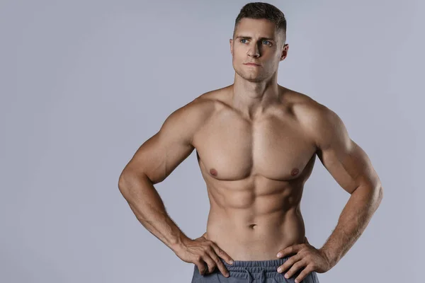 Hombre Joven Culturista Mostrando Cuerpo Muscular Sobre Fondo Gris — Foto de Stock