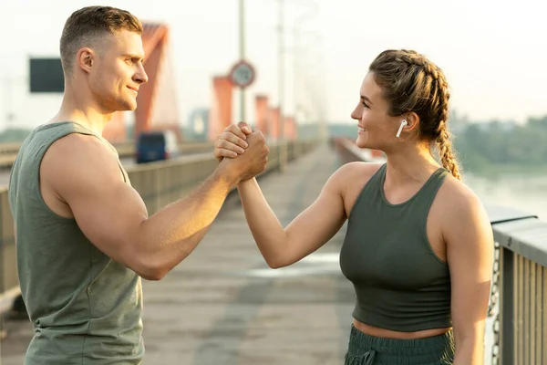 Happy athletic couple making handshake during fitness workout on city street