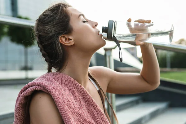 年轻疲惫的女人在户外运动后喝水 — 图库照片