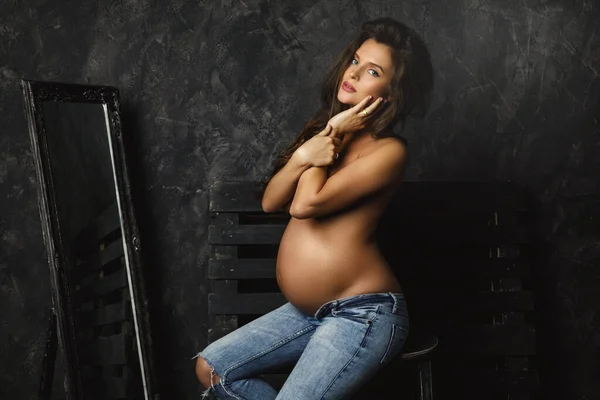 演播室里穿着漂亮长发牛仔裤的年轻孕妇的画像 — 图库照片