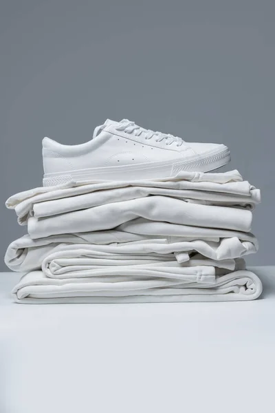 Stapel Witte Kleding Stijlvolle Trainers Grijze Achtergrond — Stockfoto