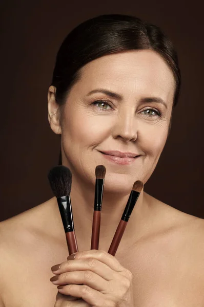 Beautiful Middle Aged Woman Makeup Brushes Brown Background — Stock Photo, Image
