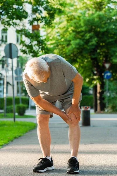 Starszy Mężczyzna Cierpiący Ból Kolana Podczas Treningu Joggingowego Parku Miejskim — Zdjęcie stockowe