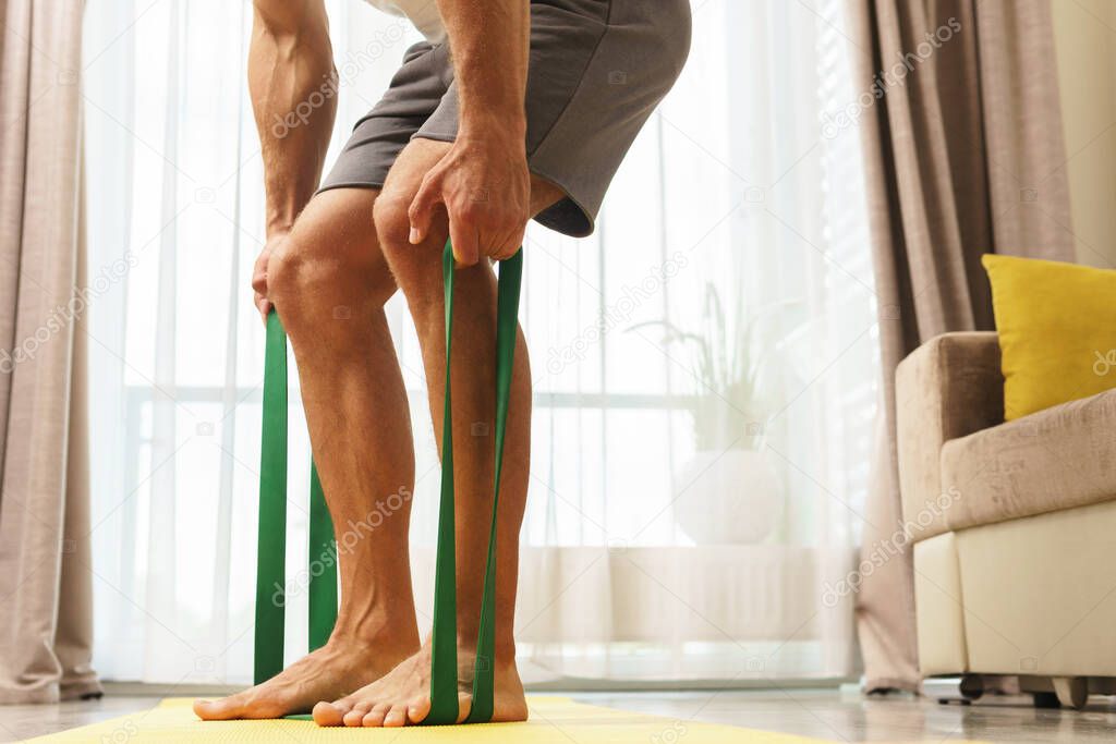 Young and muscular man during home workout with a resistance rubber bands