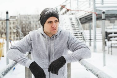 Genç atletik adam kış antrenmanı sırasında paralel barlarda dalış yapıyor.