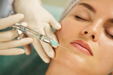 Kadın müşteri, tıbbi estetik kliniğinde yüz ameliyatından önce lokal anestezi yaptırıyor.