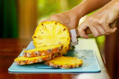 Yakın plan bıçak ve taze olgun ananas dilimleri.