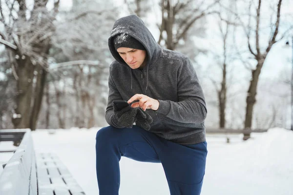 Jonge Sporter Met Smartphone Tijdens Wintertraining Besneeuwd Stadspark — Stockfoto