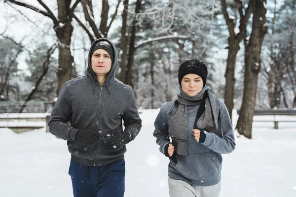Młoda Sportowa Para Biegnie Zaśnieżonym Parku Podczas Zimowego Treningu Joggingowego — Zdjęcie stockowe
